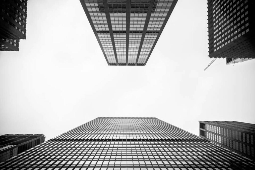 A black and white worm's eye view of towering skyscrapers illustrating urban architecture.